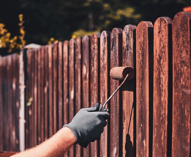 man-protective-gloves-is-painting-wooden-fence-bright-summer-day_613910-17100